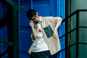 戴眼镜的年轻人站在一扇蓝色门前接电话