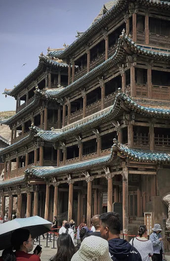 城市中的一座大型建筑 周围有大量人群和雨伞。