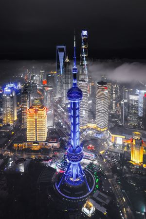 夜晚的城市照片 有雾、云、灯光、建筑和一座高塔。