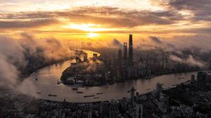 夕阳或日出时城市的 aerial view 天空中弥漫着雾气和云彩。