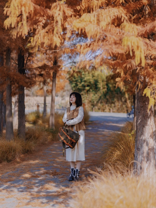 一位穿着白大褂的年轻女子走在一条树木成荫的小径上