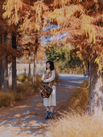 一位穿着白大褂的年轻女子走在一条树木成荫的小径上