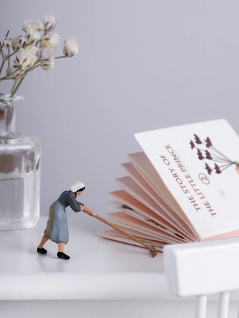 一个小人物雕像 旁边放着一些书和一个花瓶