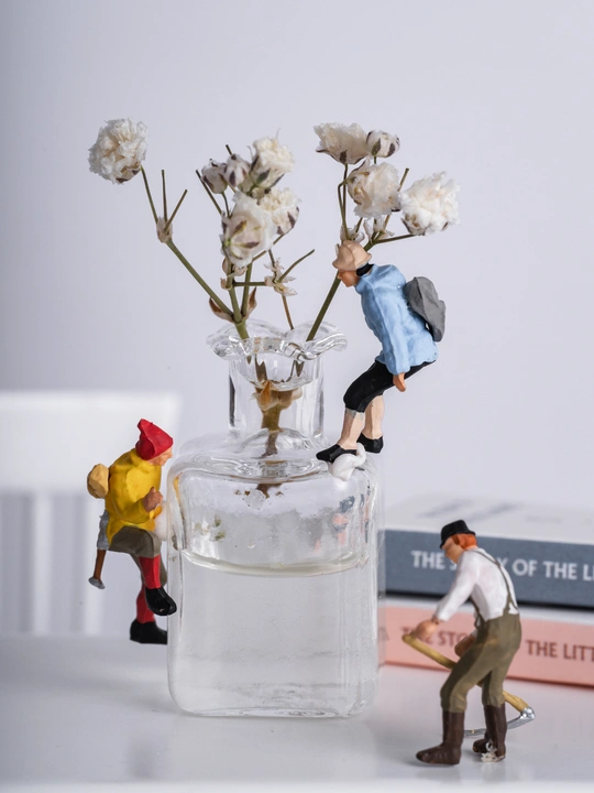 桌子上的一个小花瓶 旁边放着一些书和几个小雕像