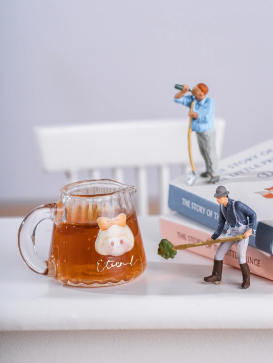 一个人的小雕像 桌上放着一杯茶和一些书