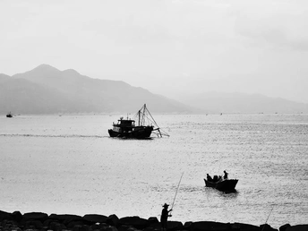 远处有山的大型水域上漂浮着一艘小船 船上有人。