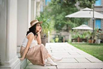 一个穿着白色连衣裙和白色靴子的漂亮年轻女子坐在一栋楼的台阶上