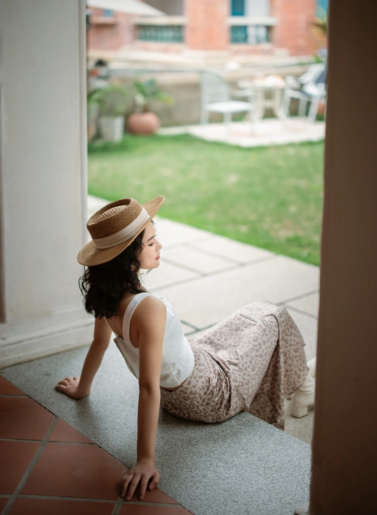 一个戴着帽子的小女孩坐在地板上 从一所房子的前门向外看