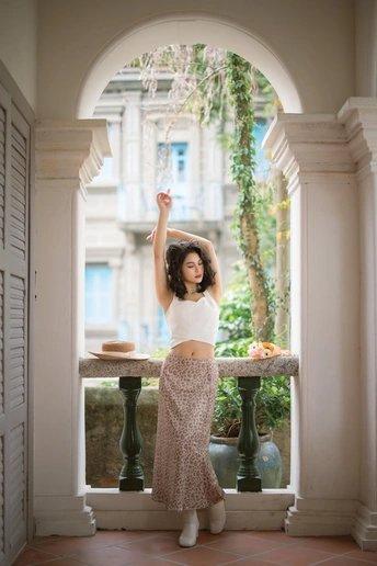 一个穿着白裙子的年轻女子站在阳台上 伸出双臂