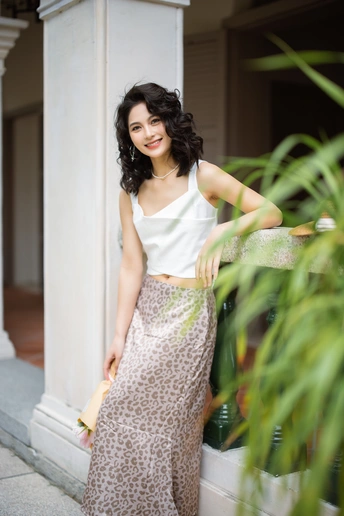 一个穿着白裙子的年轻漂亮女人站在柱子旁边