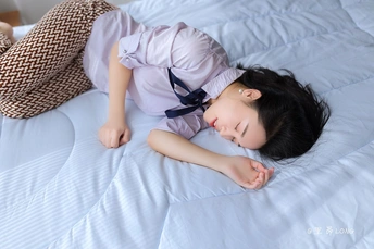 一个年轻女子躺在带有蓝色枕头的床上 一个小女孩躺在床上。