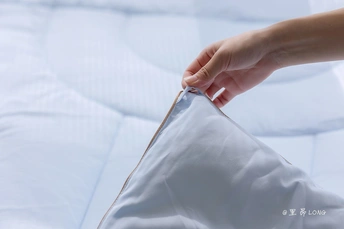 一只手正在床上一边卷着枕头一边向床单上放