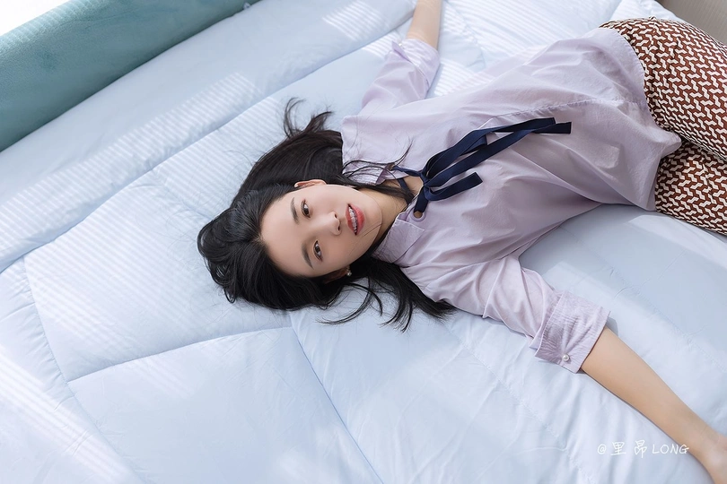 一个穿着睡衣的年轻女子躺在床上的一张床上垫子上。