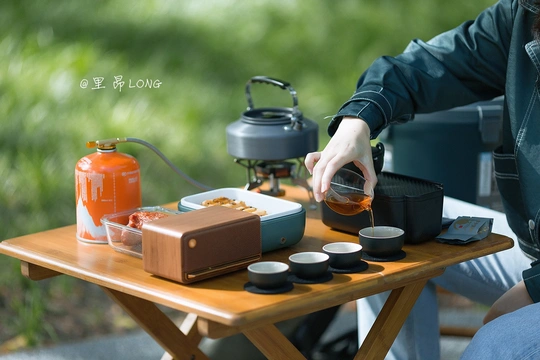 一个男子在户外桌子上倒茶入杯