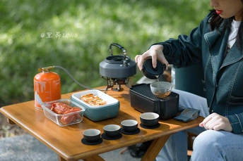 一个妇女坐在桌子旁边 正在倒茶。