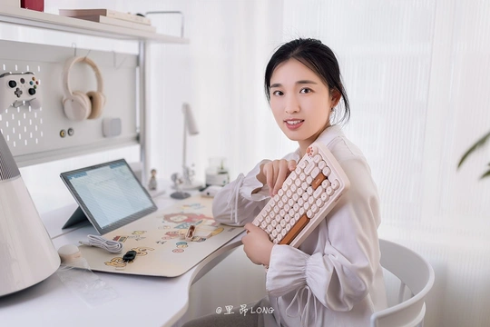 一个年轻女子坐在办公桌前 手里拿着键盘。