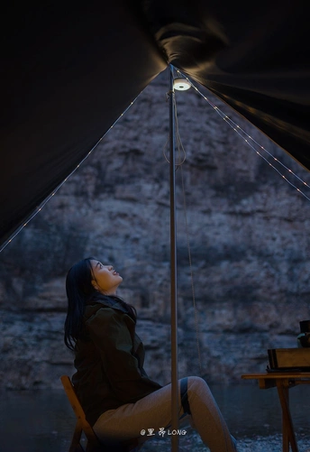 一个坐在帐篷里夜晚点亮的椅子上的女人