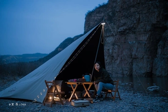 一位妇女在帐篷前夜间的桌子旁坐着