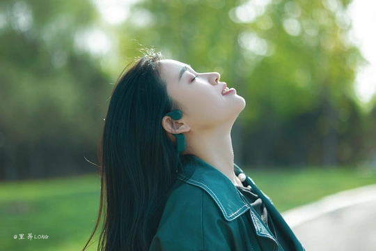 一位美丽的女子穿着绿色 闭着眼睛仰望天空的肖像。
