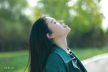 一位美丽的女子穿着绿色 闭着眼睛仰望天空的肖像。
