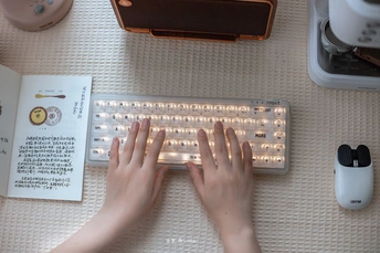 一位女性手握键盘和鼠标 旁边放着一本书和鼠标垫。