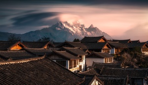 中国一个村庄的房顶上笼罩着覆雪的山峰。