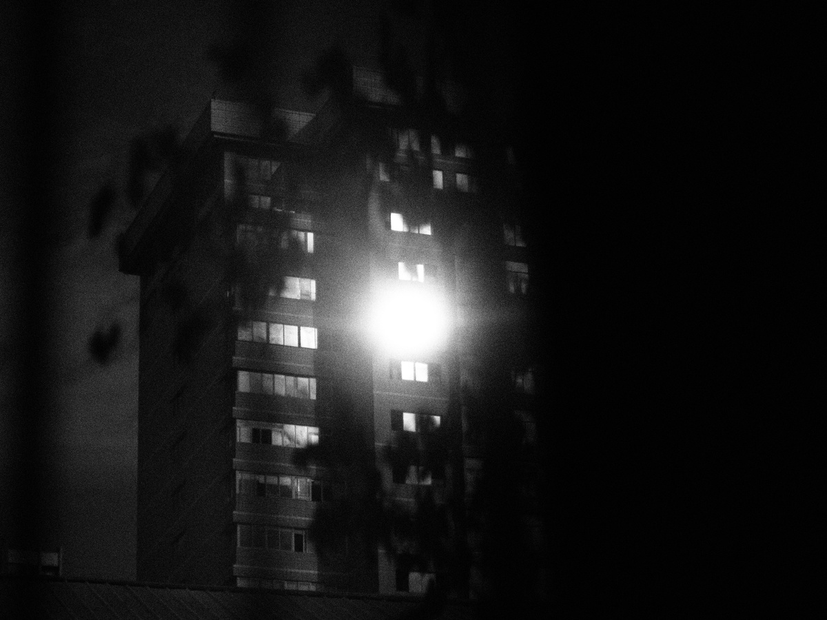 夜晚一条黑暗的街道 一座被路灯照亮的高楼