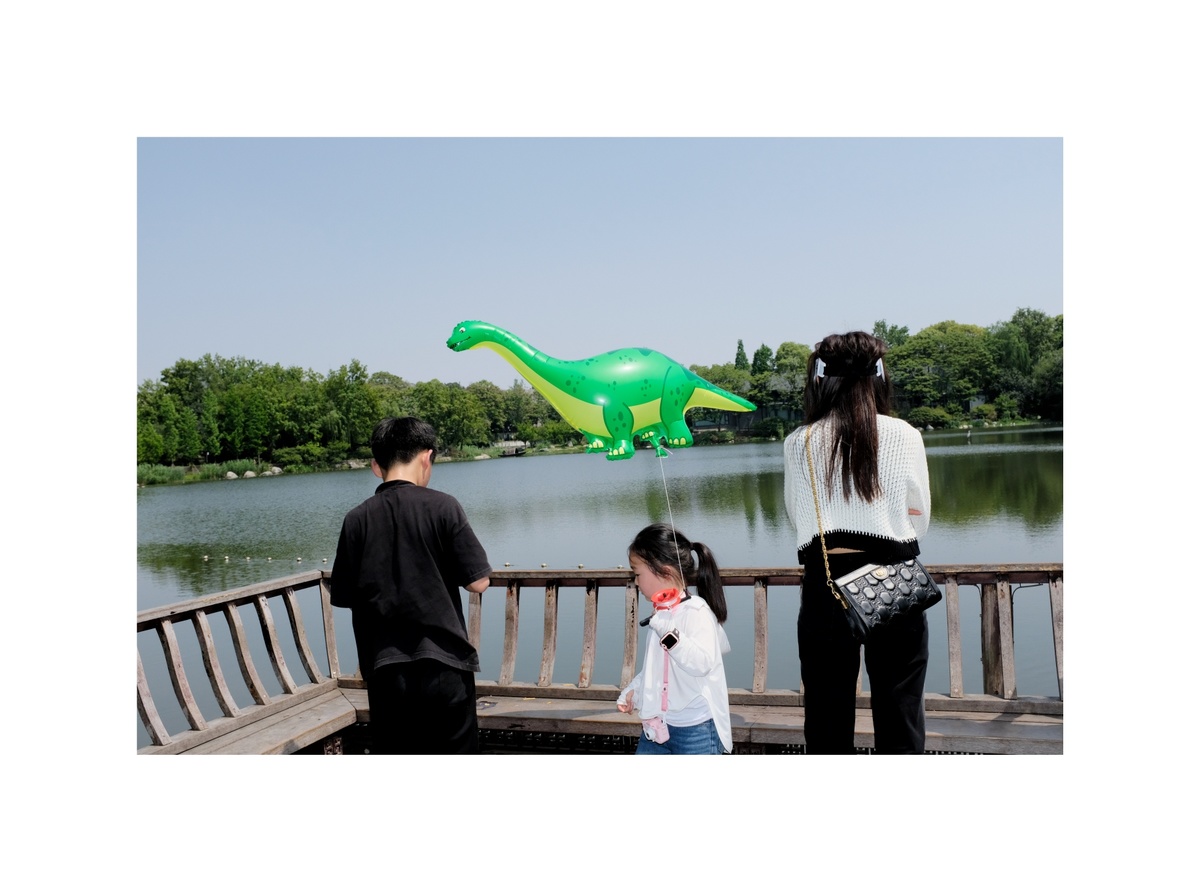 一家子在水中看着一个恐龙形状的气球