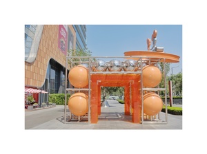 在一个橙色建筑前有一个大橙色球雕塑。