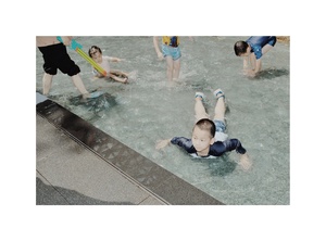 一个年轻男孩在游泳池里 人们在水里玩耍。