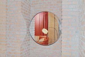 一个在砖墙上的圆形镜子反射出一个红色的房间