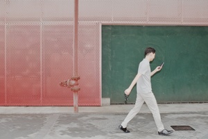 一名年轻人走在街上 低头看着手机