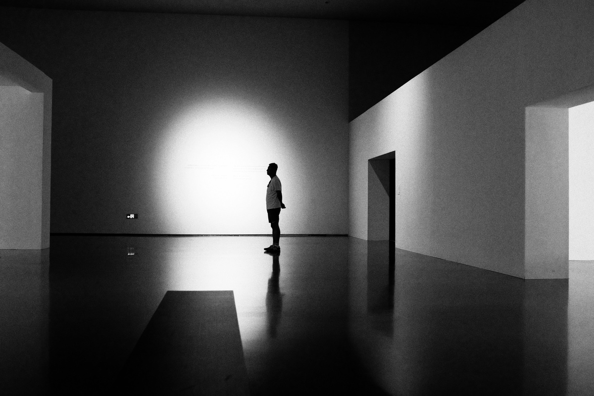 一个黑白艺术作品 描绘了一个站在黑暗房间里的男人 在墙上投下阴影。