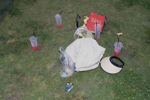 从上往下看草坪上的垃圾 包括一顶帽子、塑料瓶、眼镜和饮料躺在草地上。