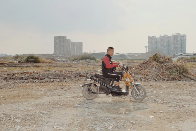 一位年轻人骑摩托车在尘土飞扬的道路上