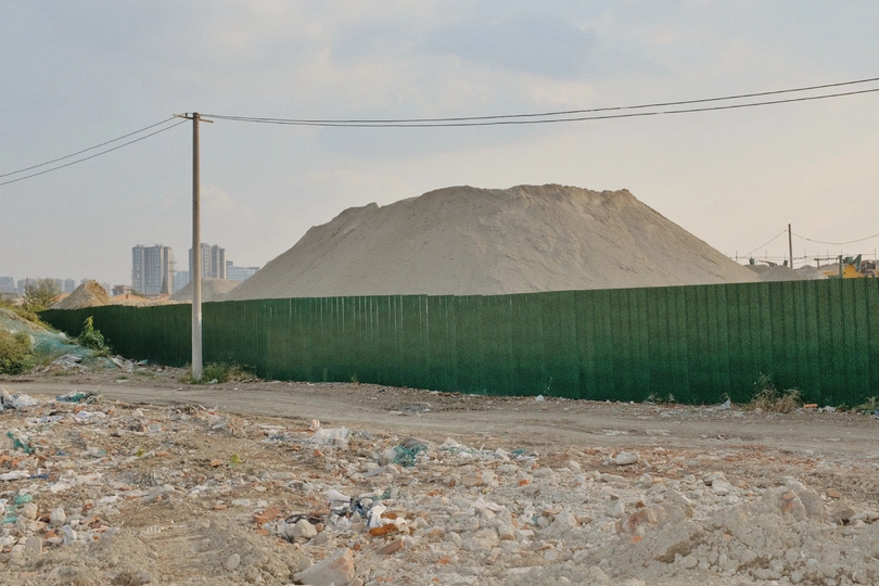 背后有一座绿色的围墙后面有一堆泥土