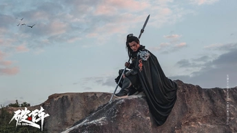 一个人站在一块石头上持有一把剑