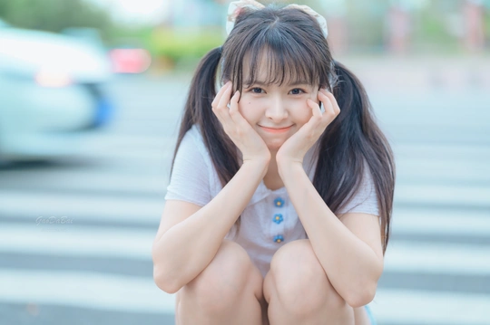 一位双手紧握坐在街道台阶上的年轻女子