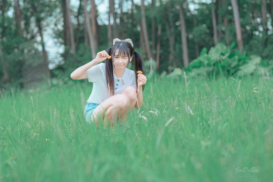 一个小女孩坐在高高的绿草地里梳头