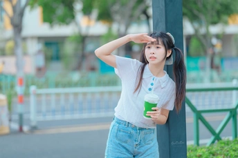 公园里 一个拿着咖啡的年轻女子站在一根杆子旁
