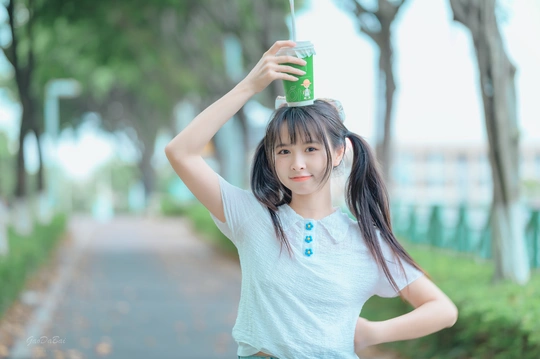 一个年轻女孩手里拿着一杯水 头上戴着一个绿色的杯子