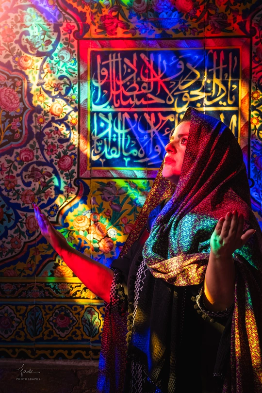 一位站在彩色艺术墙和 stained glass 前的美丽女士