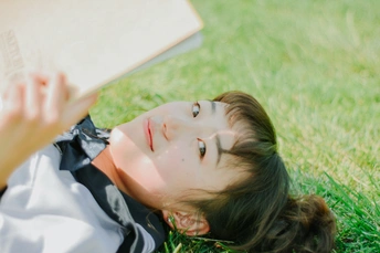 一个年轻女子躺在草地上阅读一本书