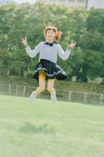 一个小女孩穿着校服在草地上跳起来