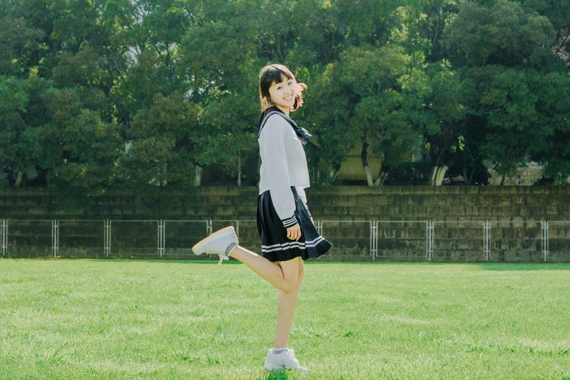 一位穿着连衣裙的年轻女子在草地上扔飞盘。