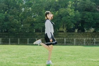 一位穿着连衣裙的年轻女子在草地上扔飞盘。