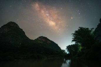 夜晚的天空中有水、山和星星的湖泊