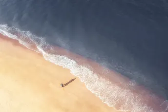 一片沙滩上有一艘船在岸边 水中有波浪的空中视角