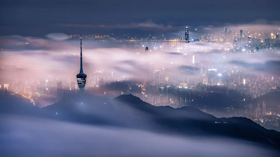 夜晚的雾中城市 背景是山脉