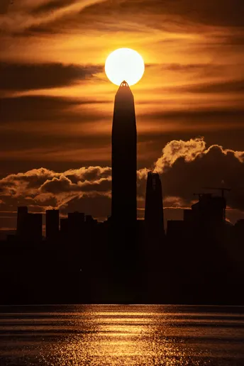 夕阳西下 背景是高楼大厦和前景是水面。